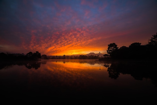 A sunset over a lake with a reflection of the mountains in the water.