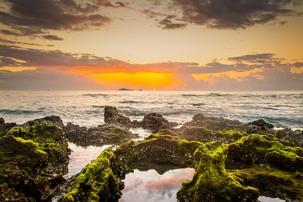 Sunset landscape on the beach rocks in foreground