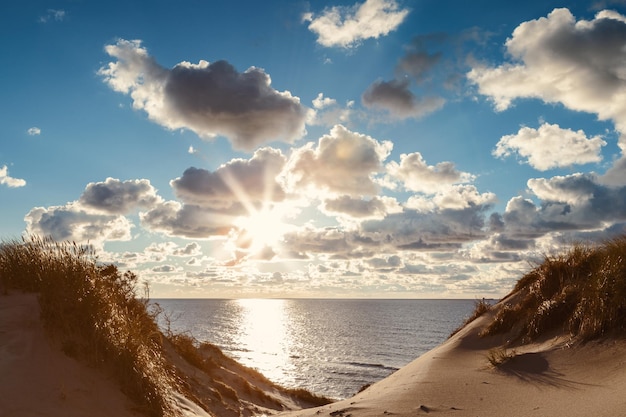 Sunset landscape of the shore of Baltic sea with fluey cloudssun rays and sand dunes