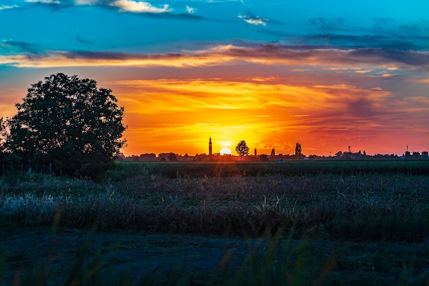 Закат в пейзаже с колокольней, деревьями и сельской местностью