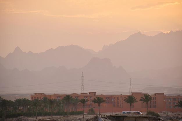 Sunset landscape with remote hotel complex against dark mountain peaks in egyptian desert