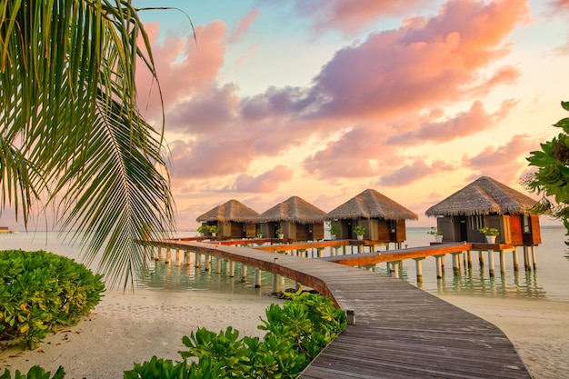 Sunset at a luxury beach resort. Water bungalows with beautiful twilight sky and sea in Maldives