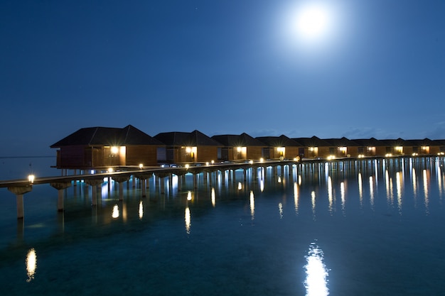 Закат на острове Мальдивы, роскошные водные виллы курорта и деревянный пирс. Красивое небо и облака и пляж фон для летних каникул отдыха и концепции путешествия