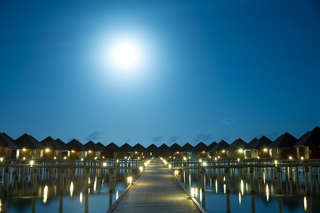 Закат на острове Мальдивы, роскошный курорт с водными виллами и деревянный пирс. Красивое небо и облака и пляжный фон для летних каникул и концепции путешествий