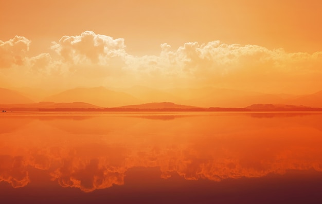 Sunset over mountain lake with reflection in calm water surface