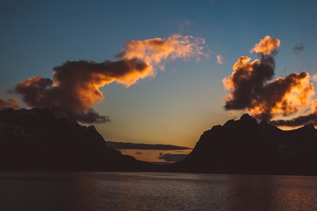 Sunset over the mountains by the sea. Silhouette of the mountains. Beautiful clouds.