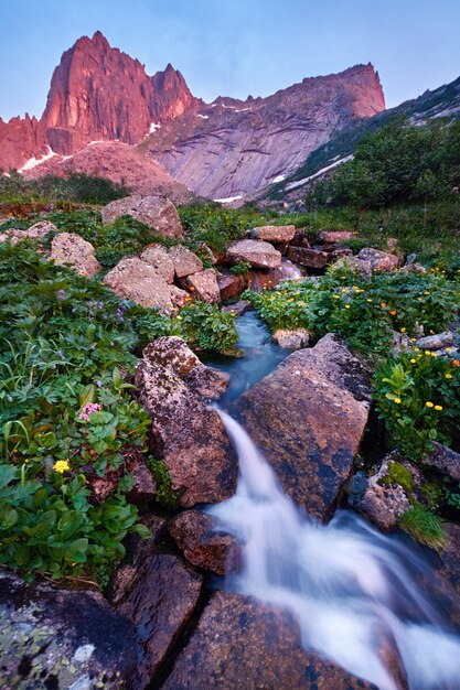 Sunset in mountains near river. Sunlight reflected on mountain tops