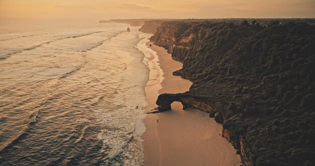 Photo sunset ocean seascape with waves at rock wall on sand beach aerial view nobody nature scenery