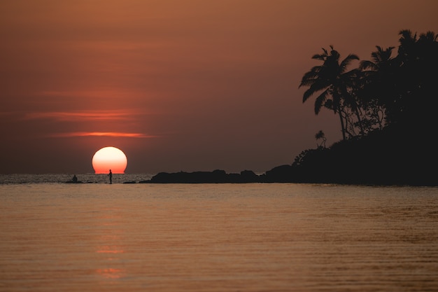 Sunset ocean view. Sun above the sea on orange sky.