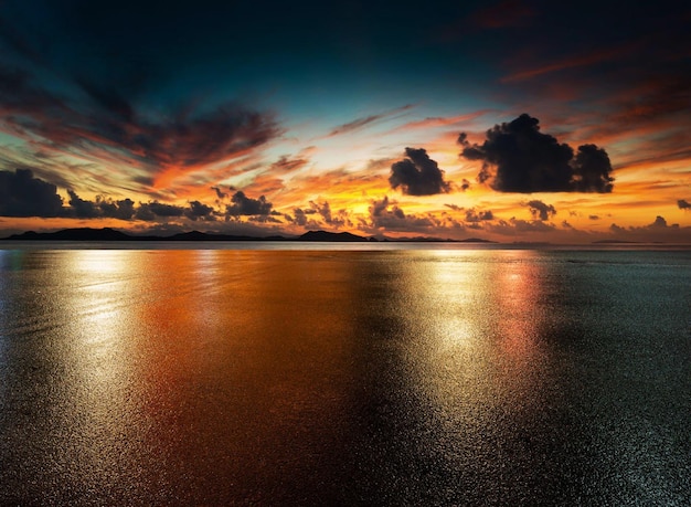 A sunset over the ocean with a blue sky background and clouds