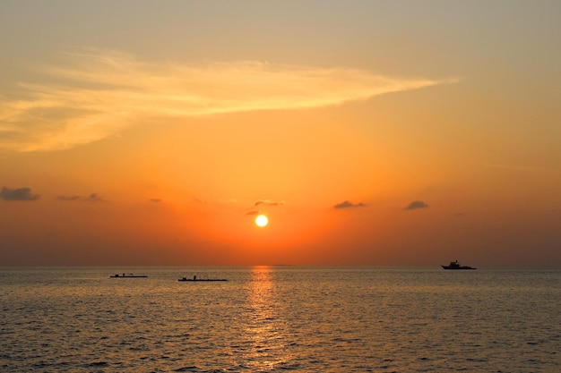 写真 ボートとモルディブ島の夕日と旅行ボートからの海の景色の太陽光の反射