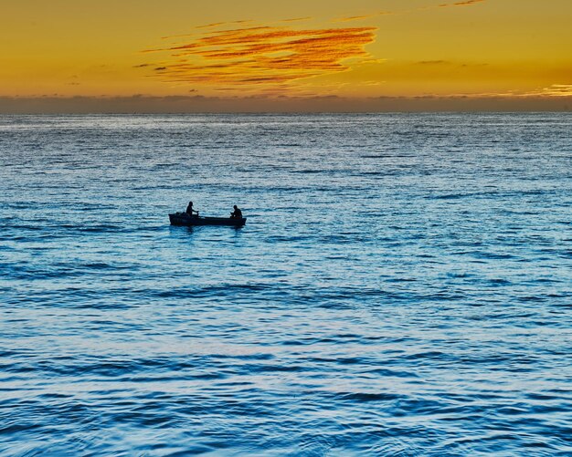 写真 夕日とカヌーの人がいるビーチの夕日