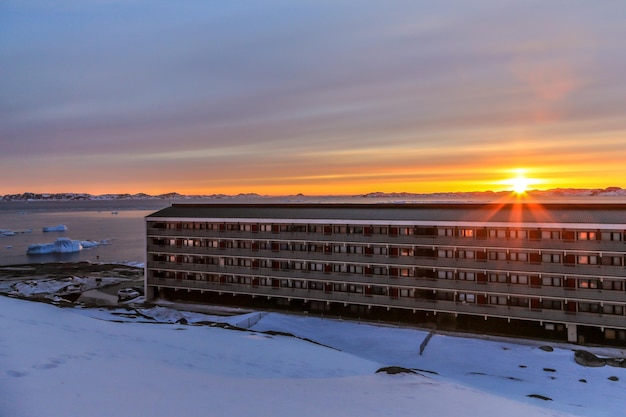 写真 北極圏の首都ヌーク市グリーンランドのフィヨルドと生活ブロックに沈む夕日