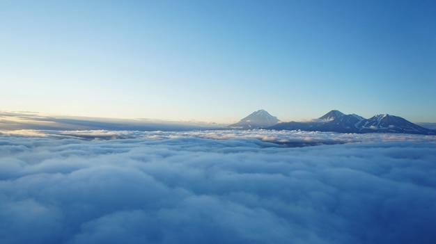 カムチャツカ火山の夕日の写真。雲の上の高地。雲の層と山の上の影