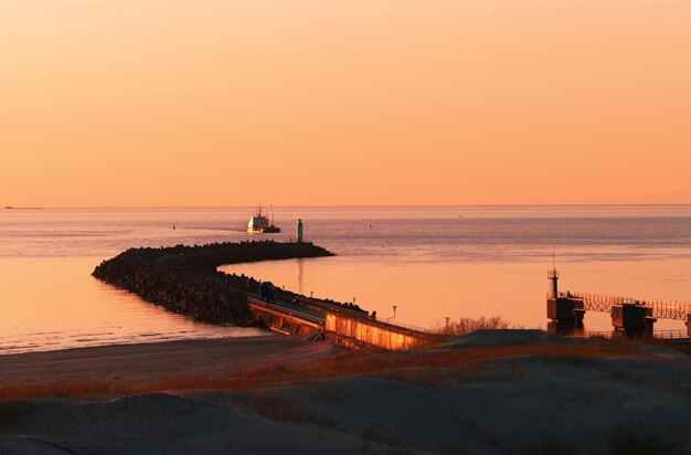 Photo sunset at the pier on baltic sea in ventspils. ventspils a city in the courland region of latvia. latvia is one of the baltic countries