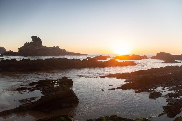 Photo sunset on rocks at castelejo beach, algarve, portugal