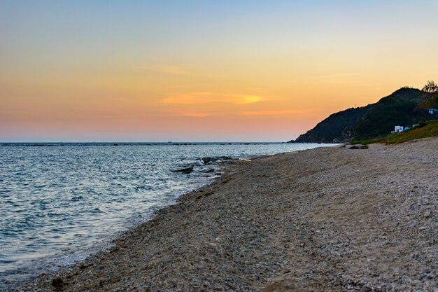 南シナ海の小東海湾の海岸にある夕日、砂、澄んだターコイズブルーの海、サンゴ礁。三亜、海南島、中国。自然の風景。