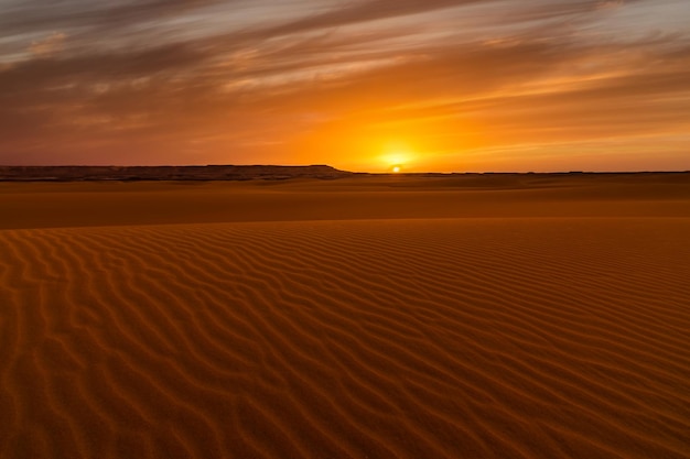 Sunset over the sand dunes in the desert Arid landscape of the Sahara desert