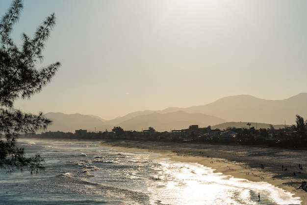 Foto tramonto alla spiaggia di saquarema a rio de janeiro, brasile. famoso per le onde e il surf. chiesa in cima alla collina.