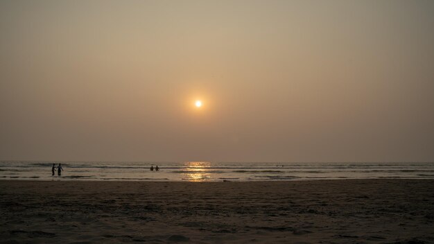 Sunset over sea and beach Cloudless sundown sky over waving sea and sandy beach in evening on resort