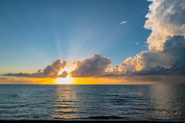 曇り空と海のビーチの日の出に沈む夕日