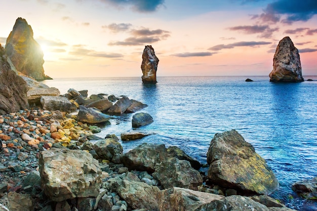 Sunset on the sea above big rocks. Landscape with coast and dramatic sky