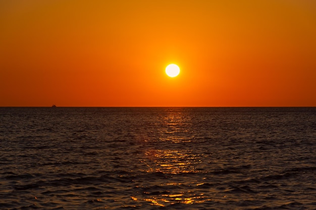 サンセットシーボート。丸いオレンジ色の太陽とロマンチックな夏の風景。自然界のミニマリズム。