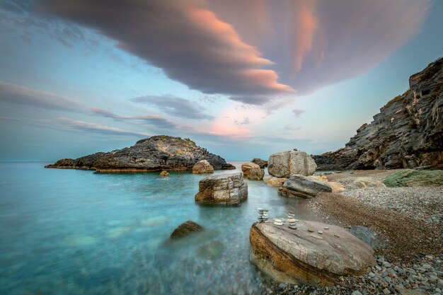사진 해가 지는 바다 해변에서 저녁 시간 큰 바위와 다채로운 극적인 구름 아름다운 자연 풍경
