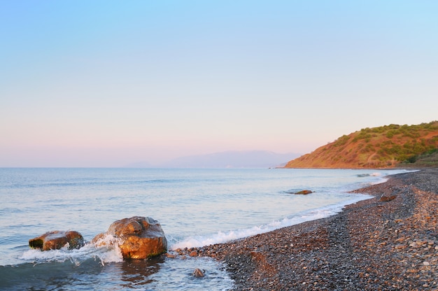 Закат на берегу моря, каменистый пляж