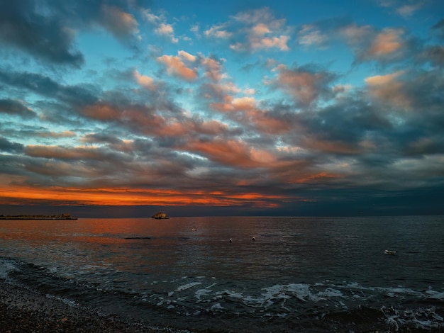 Закат на берегу моря с оранжево-красными облаками