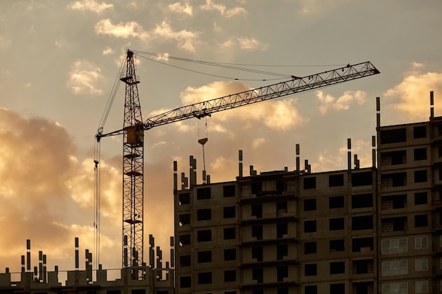 Sunset silhouettes of highrise buildings under construction with cranes