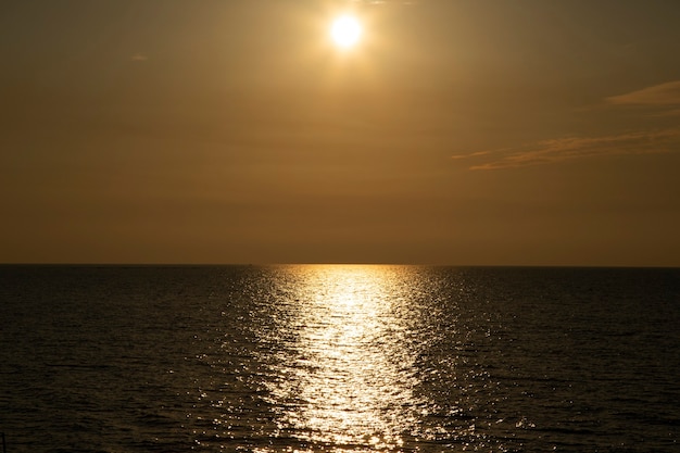 サンセットシルバーベージュトーン。夕焼け空と雲の切れ間から太陽が降り注ぐ穏やかな海。瞑想の海と空の背景。静かな海の景色。水上の地平線。