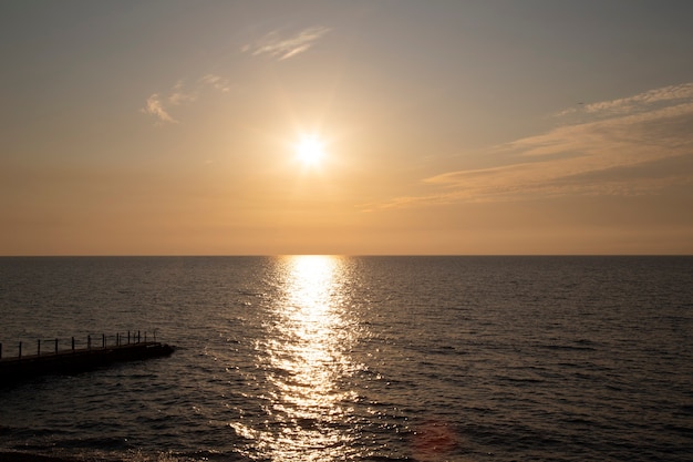 サンセットシルバーベージュトーン。夕焼け空と雲の切れ間から太陽が降り注ぐ穏やかな海。瞑想の海と空の背景。静かな海の景色。水上の地平線。