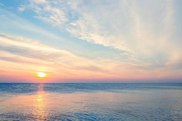 Cielo al tramonto sul mare la sera con la luce solare arancione di nuvole colorate