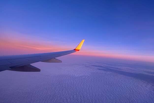 空と飛行機の翼に沈む夕日、飛行機の窓からの眺め