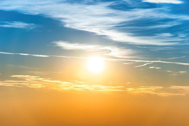 Sunset in the sky with blue orange clouds and big sun