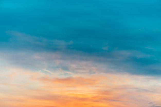 Sunset sky with orange yellow light clouds. Colorful smooth blue sky gradient. Natural background of sunrise. Amazing heaven at morning. Slightly cloudy evening atmosphere. Wonderful weather on dawn.