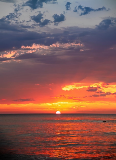 Sunset sky with reflections in water sunlight and colored orange clouds