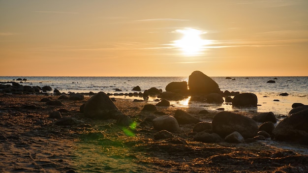 Sunset stenen strand met kleine en grote rotsen voor de verlichte zee