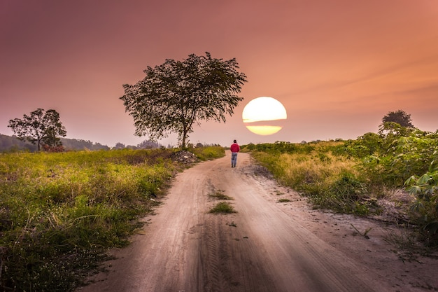 Foto ora del tramonto un uomo che cammina da solo alla strada campestre.