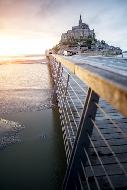 フランスの潮の干満時に橋のある有名なモンサンミッシェル修道院の夕日の景色