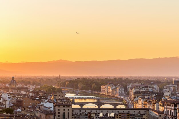 Foto vista del tramonto di firenze in italia con un aereo di linea che si solleva