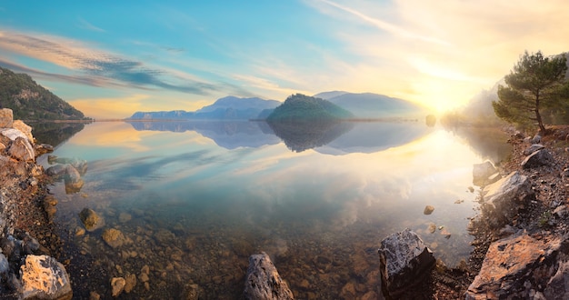 Sunset view from the rocky shore of a mountain lake. Panorama