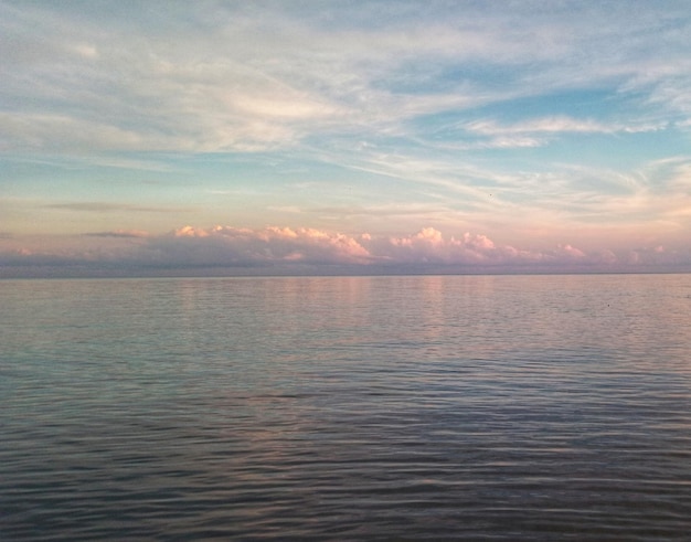 A sunset over the water with a cloudy sky in the background