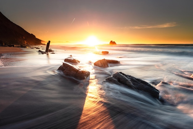 写真 ビアリッツ バスク カントリーのイルバリッツ ビーチで海の波がビーチの岩にぶつかる夕日