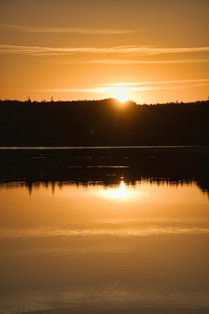 スモールアンドロマンティックな夜のムードのスウェーデンの湖に映る夕日