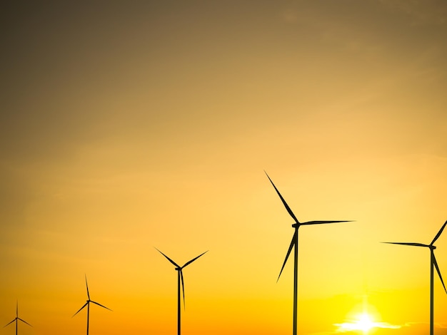 A sunset with wind turbines in the foreground and the sun setting behind it.