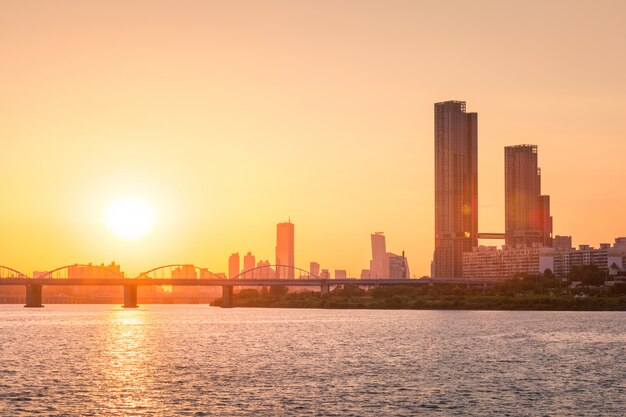 韓国のソウルのダウンタウンにある汝矣島の高層ビルとハン川に架かる橋の後ろに沈む夕日。