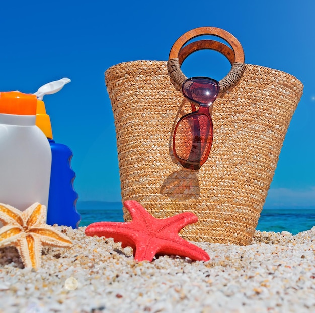 Suntan lotion and straw bag at the beach