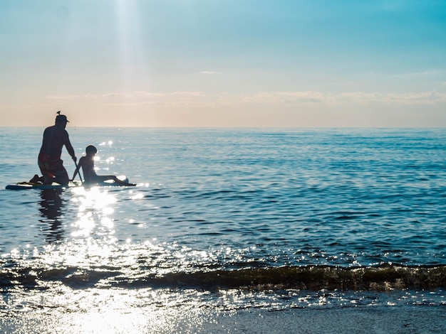 Sup surftraining vader en zon zwemmen in de open zee op SAP-surfen